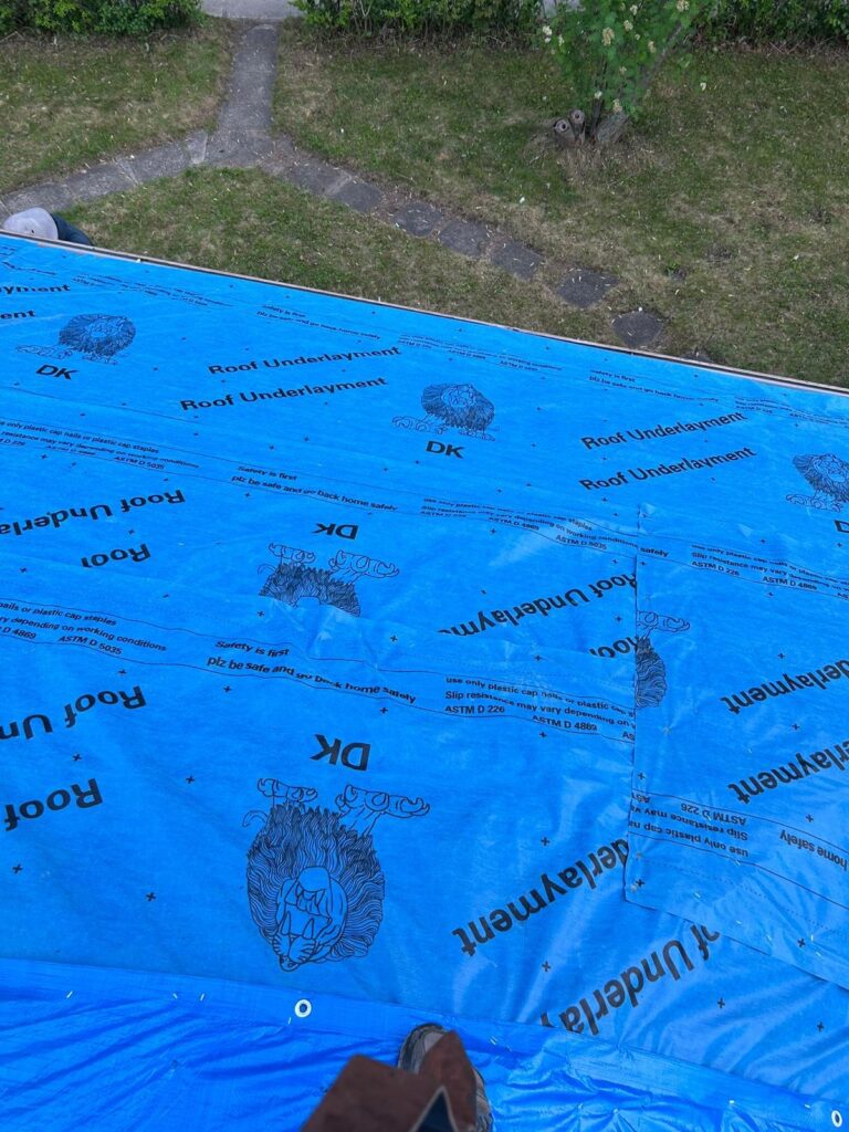 Blue roofing underlayment covering a roof during installation